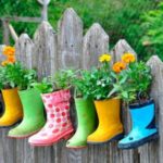 colourful rubber boots planted with flowers along a fence